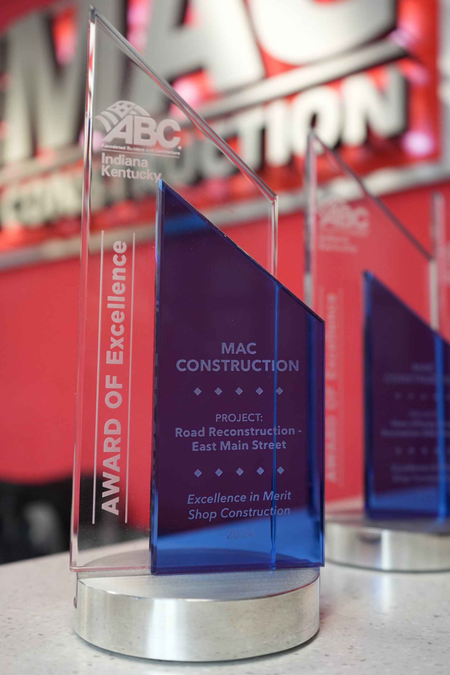 Blue and purple glass award reading 'MAC Construction' with the project 'Road Reconstruction - East Main Street' on a metal base.